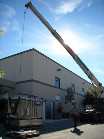 Commercial Remodels, Maintenance and Repairs: A crane lifts a evaporative tower into place inside a newly built enclosure at this manufacturing site.