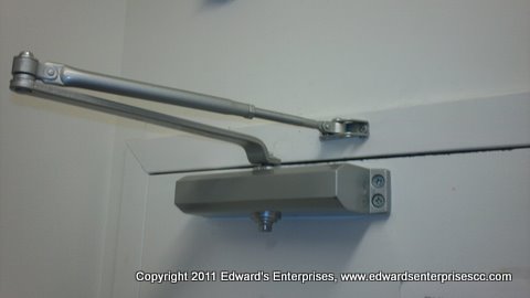 A sturdy door lever and closer assembly installed on a regular door.