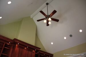 Ceiling fan with three lights at the peak of a vaulted ceiling with recessed lights to the side