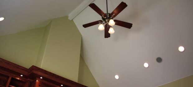 Ceiling fan with three lights at the peak of a vaulted ceiling with recessed lights to the side
