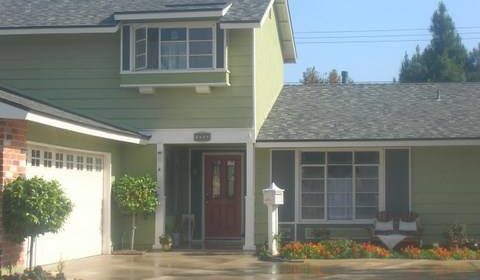 Front of two story home painted green with garage and driveway