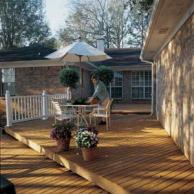 Home and wooden deck with umbrella-covered table and four chairs.