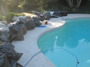 Bags filled with trash along the side of a pool