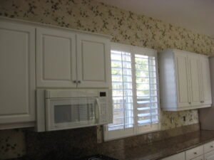 Kitchen with white cabinets being remodeled, before wallpaper removed