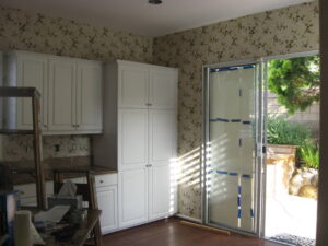 Kitchen with white cabinets being remodeled, before wallpaper removed