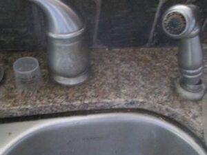 Old faucet before photo with calcium buildup on sprayer