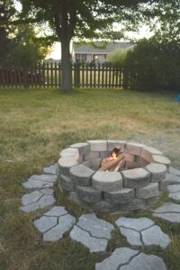 Stone fire pit on lawn surrounded by pavers