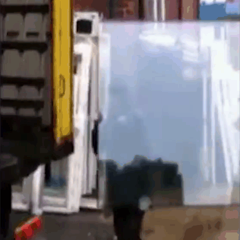 Men loading glass pane into truck miscalculate and cause it to break in their hands.