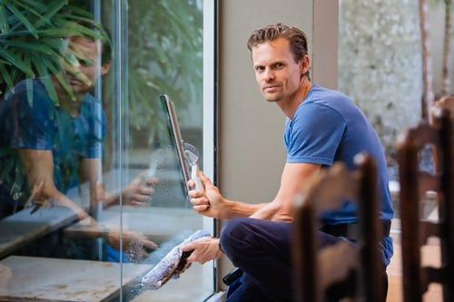 Man cleaning window from inside home