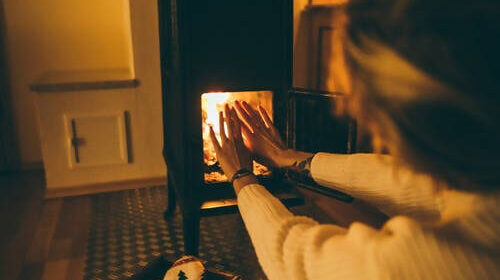 Woman warming hands by wood burning heater