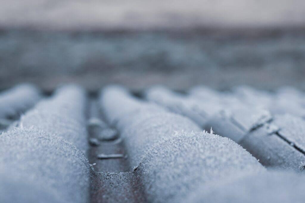 Roof shingles, like a brown Spanish tile, covered in frost