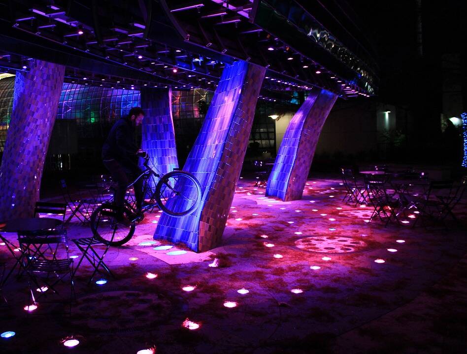 Outdoor purple-pink LED lighting, with man standing with a BMX bike