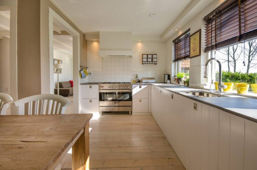 Kitchen with white oak floor, white cabinetry and walls, and light coming through the window