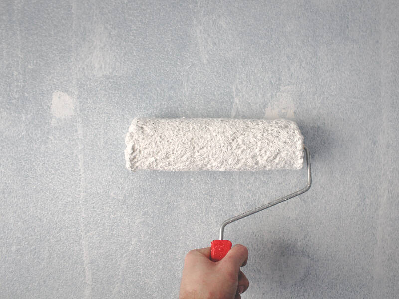 paint roller with white paint about to paint the wall