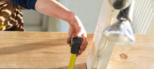 Carpenter measuring dimensions of joists from above