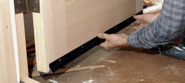 A man replacing a door sweep.