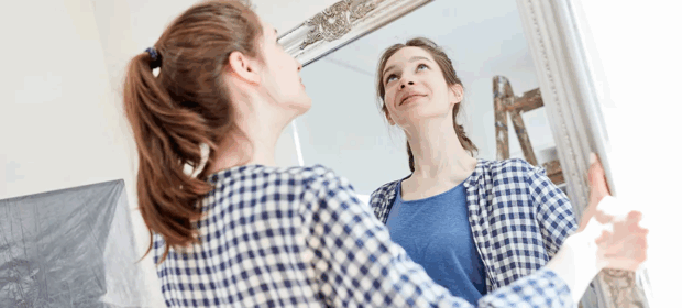 A woman hanging a mirror
